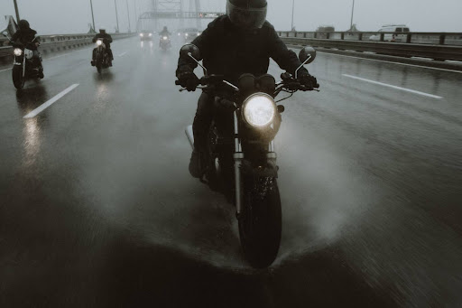 A group of bikers riding in the rain and fog on a highway